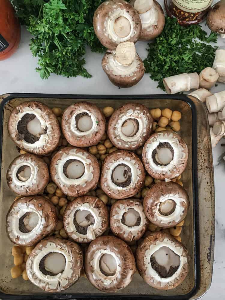 mushroom caps sitting on chickpeas in a casserole dish