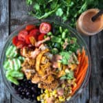 Chopped vegetable salad with vegan chicken and spicy dressing in a bowl.