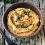 spicy hummus in a bowl with a sprinkle of parsley and hot pepper flakes