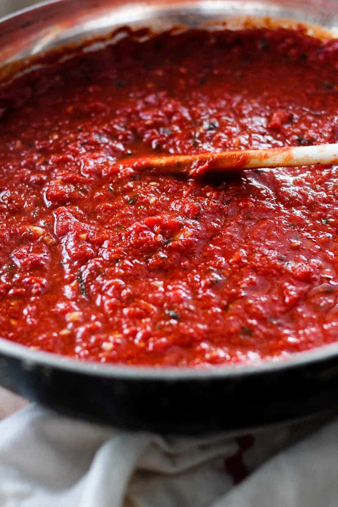 Rich red homemade marinara sauce simmering in a pan.