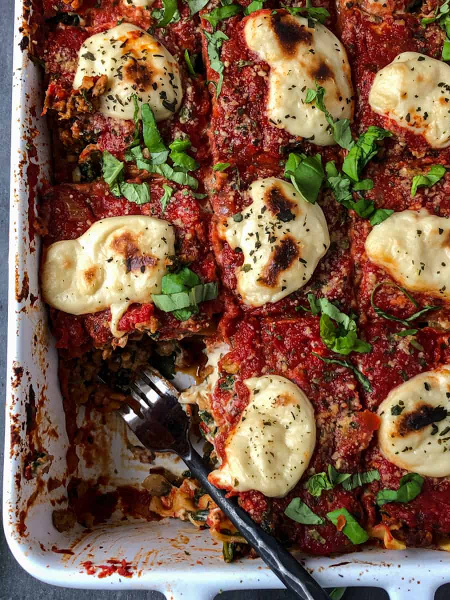 Vegan lasagna with bechamel sauce in a pan topped with melted cheese.