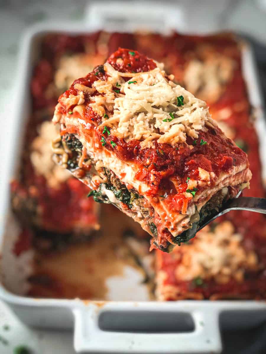 Vegan lasagna slice being lifted out of baking pan.