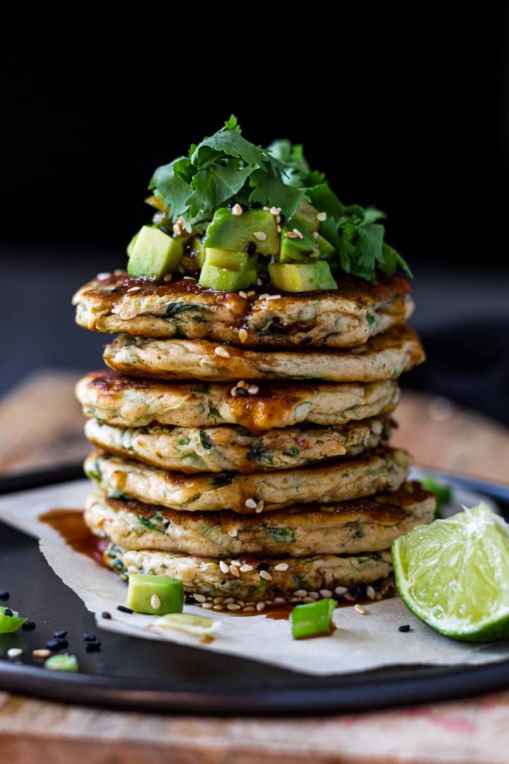 Stack of savory spinach pancakes with avocado and cilantro on top.