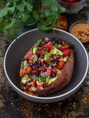 Stuffed sweet potato with taco-spiced tofu filling, avocados, tomatoes, and black beans.
