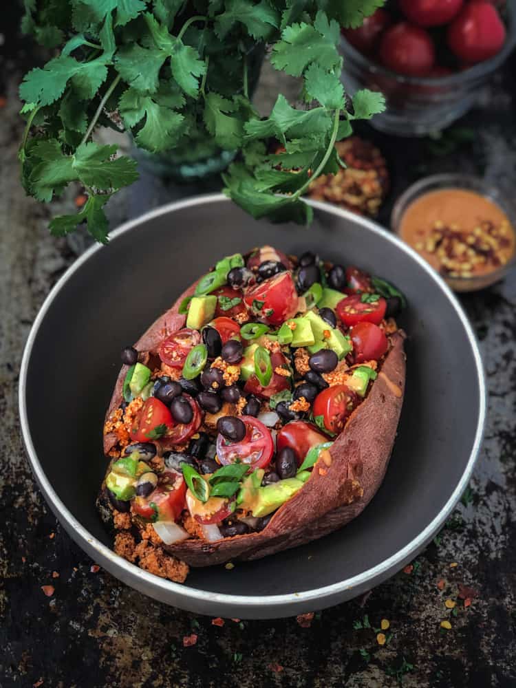 Sweet potato split open and filled with tofu taco filling, black beans, green onions, tomatoes, and avocado. Served with a bowl of spicy drizzling sauce.