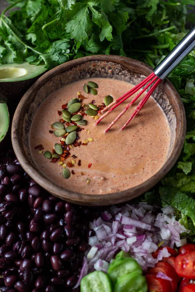 Bowl of tex-mex salad dressing in a bowl surrounded by salad ingredients.