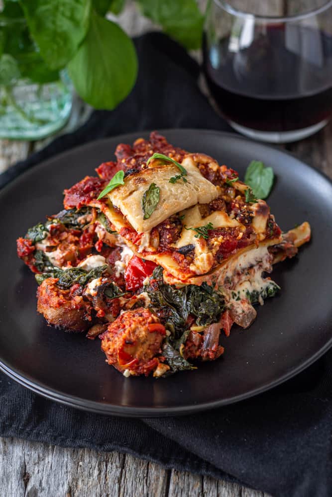 Vegan sausage lasagna on plate with a glass of wine.