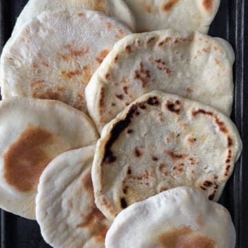 Baking tray filled with baked and fried pita bread.