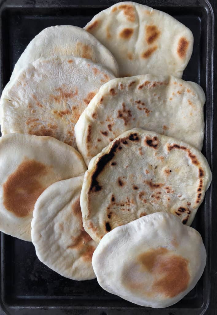 Baking tray filled with baked and fried pita bread.