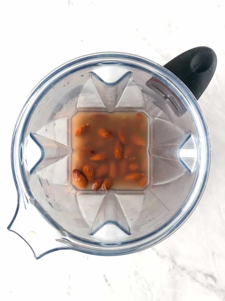 Overhead shot of Vitamix blender cup filled with almonds soaking in water.