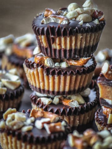 Mini peanut butter cups stacked in a tower on a plate of peanut butter cups.