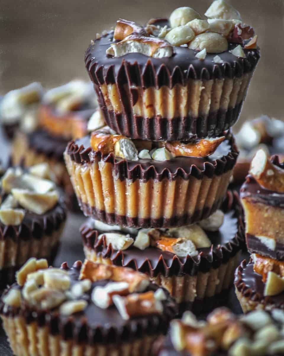 Mini peanut butter cups stacked in a tower on a plate of peanut butter cups.