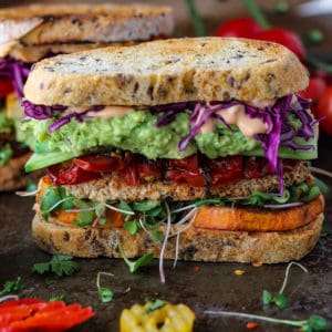 Vegetable sandwich with guacamole, tomatoes, sweet potatoes and tofu on sourdough bread.