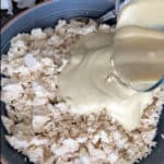 Cashew cream being poured into abowlful of crumbled tofu.