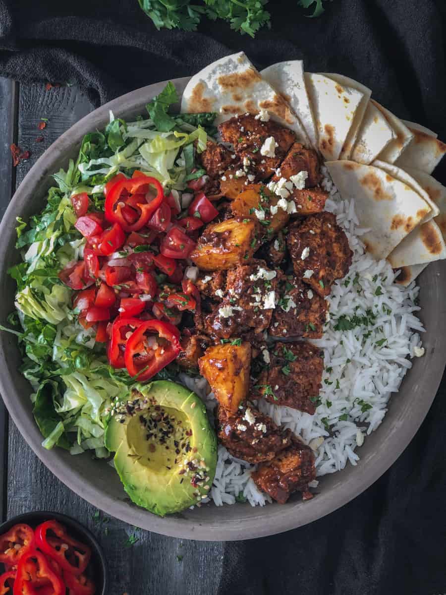 Overhead shot of buddha bowl with spicy tofu, tomatoes, avocado and rice.