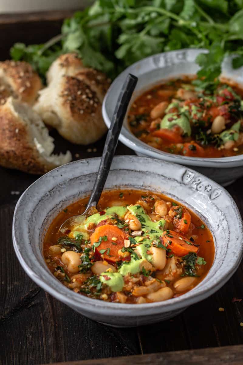 Overhead shot of vegetable bean soup with freshly baked buns.