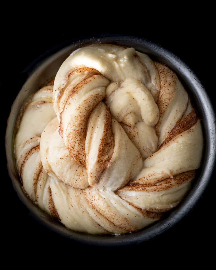 Cinnamon twist bun proofing in a pan.