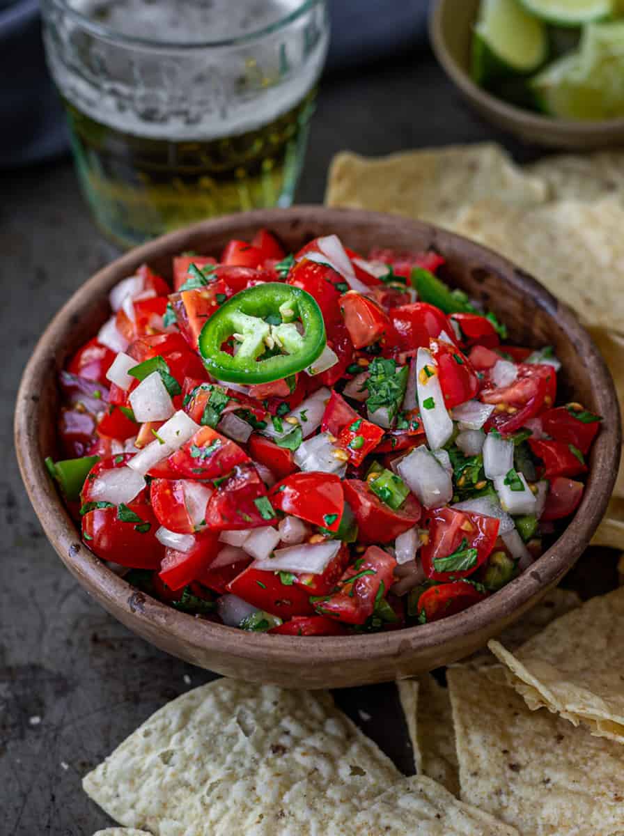 Bowl of pico de gallo on a tray of taco chips.