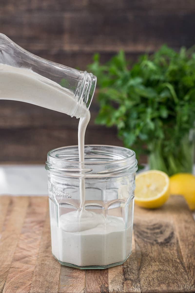 Tahini sauce being poured into a jar.