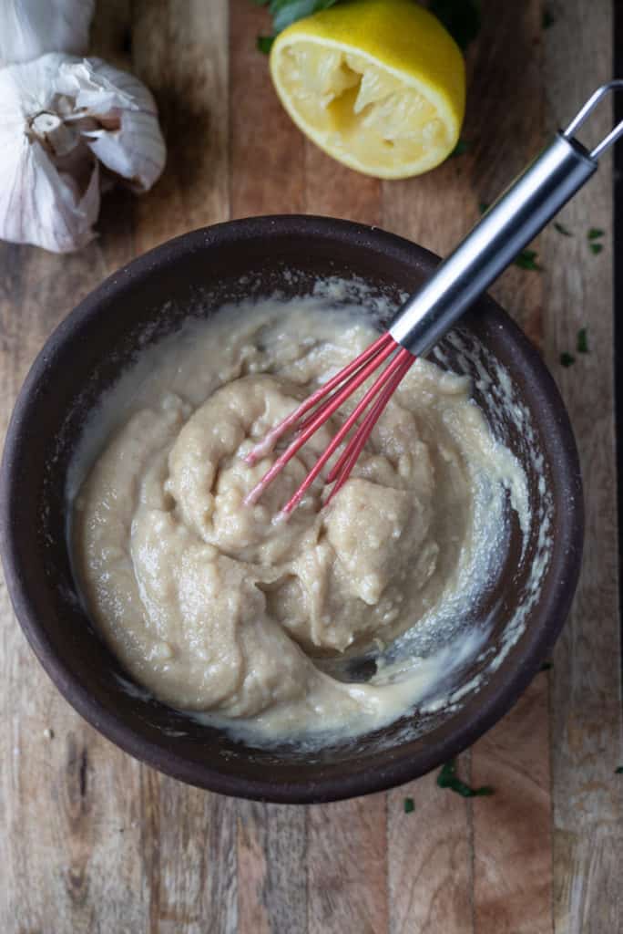 Homemade tahini sauce being whisked in a bowl.