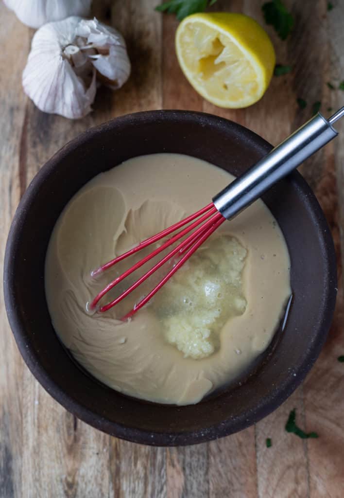 Tahini sauce being mixed in a bowl.