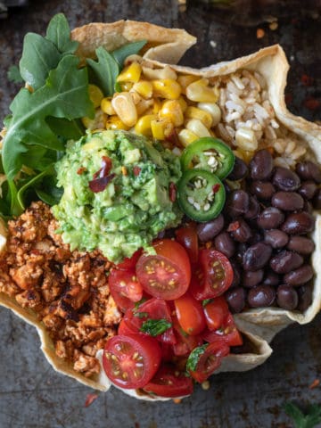 Overhead shot of taco bowl with guacamole, tofu crumble, beans, corn, and tomatoes.