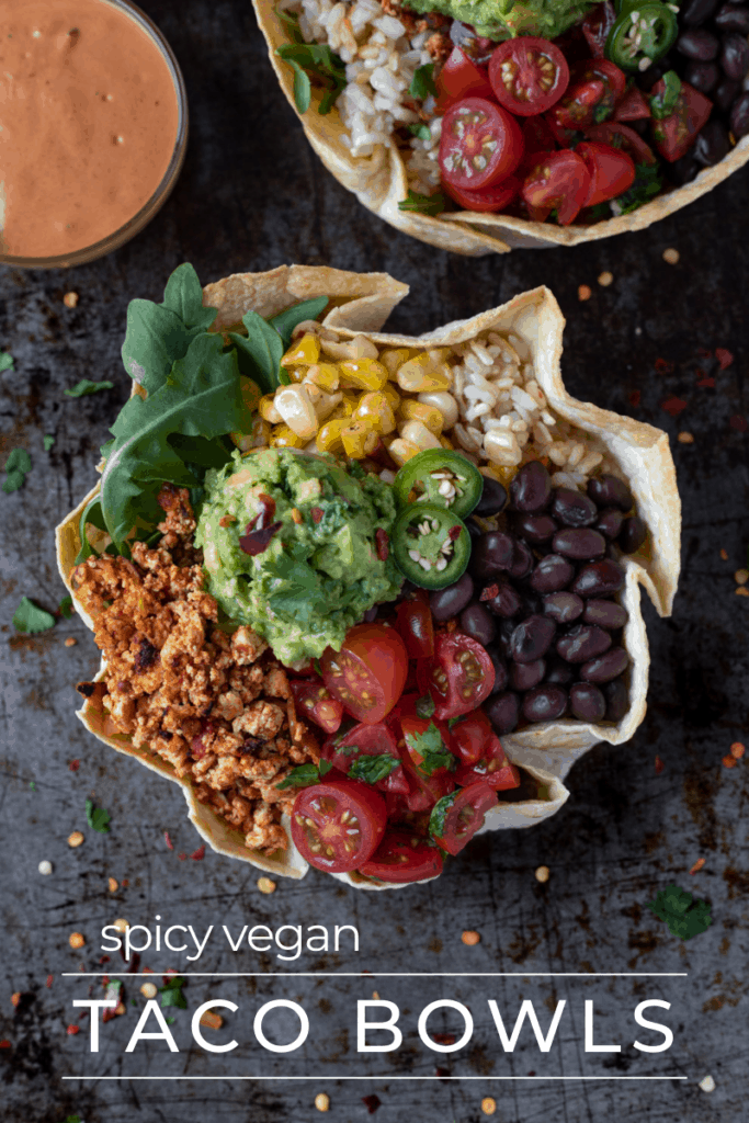 Vegan Taco bowl filled with tofu crumbles, guacamole, tomatoes and beans in a tortilla bowl.
