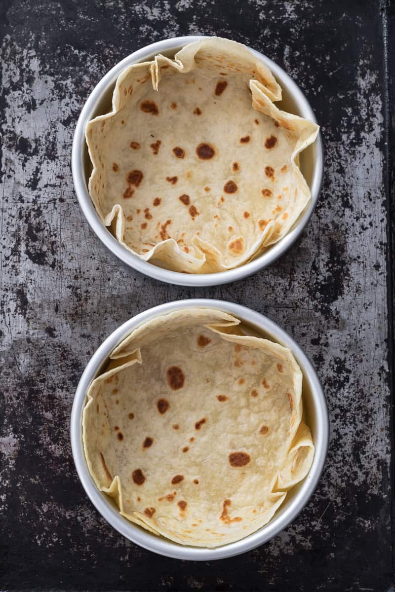 Two tortilla shell bowls on a baking sheet.