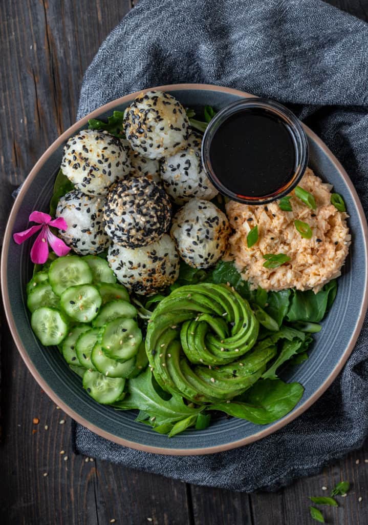 Sushi bowl with spicy vegan crab salad, rice balls and an avocado rose.