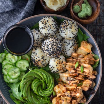 Vegan sushi bowl with tempura mushrooms, rice balls and an avocado rose.
