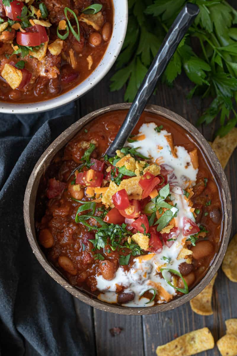 Bowls of meatless chili with sour cream tomatoes and avocado toppings..