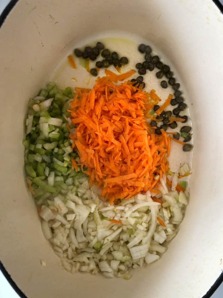Dutch oven with chopped carrots, onions and celery saute on stove.