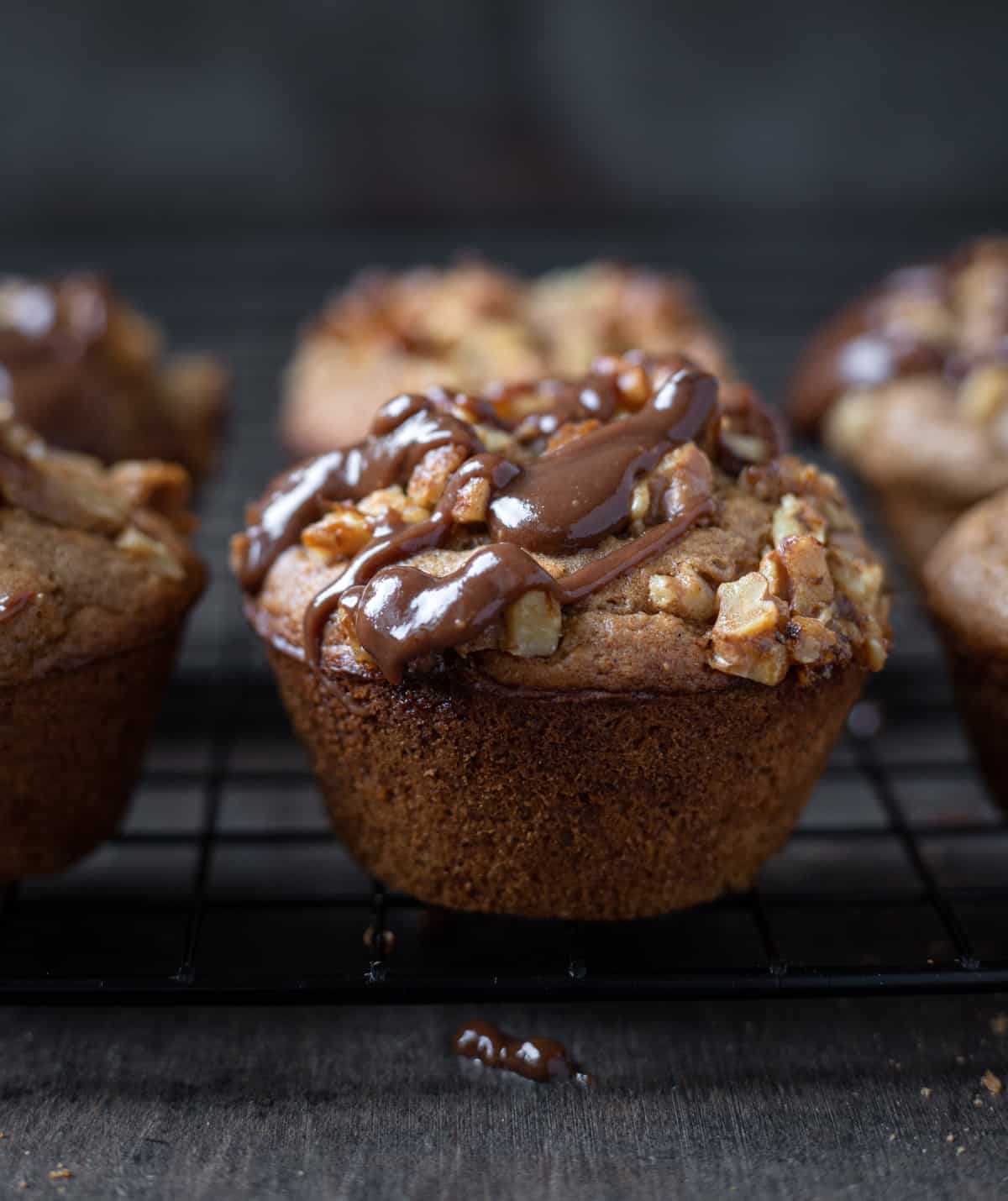 Vegan Banana Nut Muffin with chocolate drizzle sitting on cooling rack.