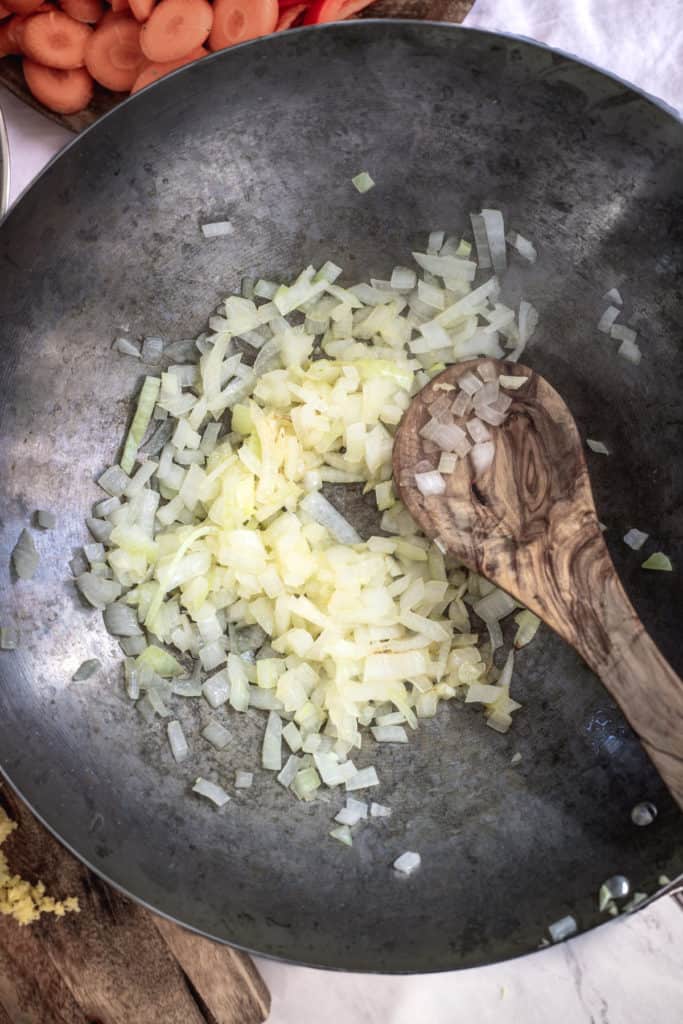 Onions and garlic being sauteed in a wok.