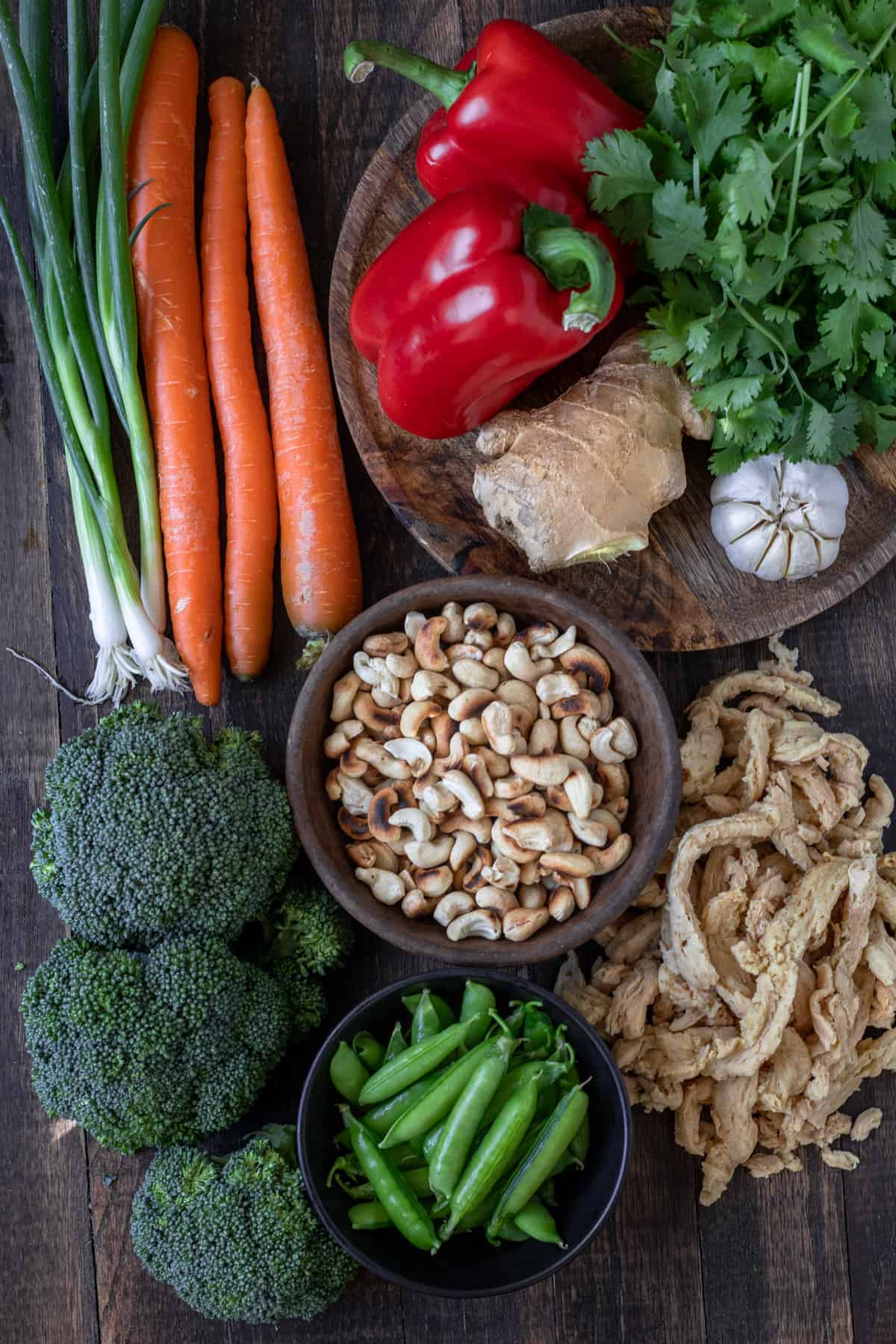 Ingredients for vegan cashew chicken including soy curls, peas, broccoli, carrots, red pepper, ginger and cashews.