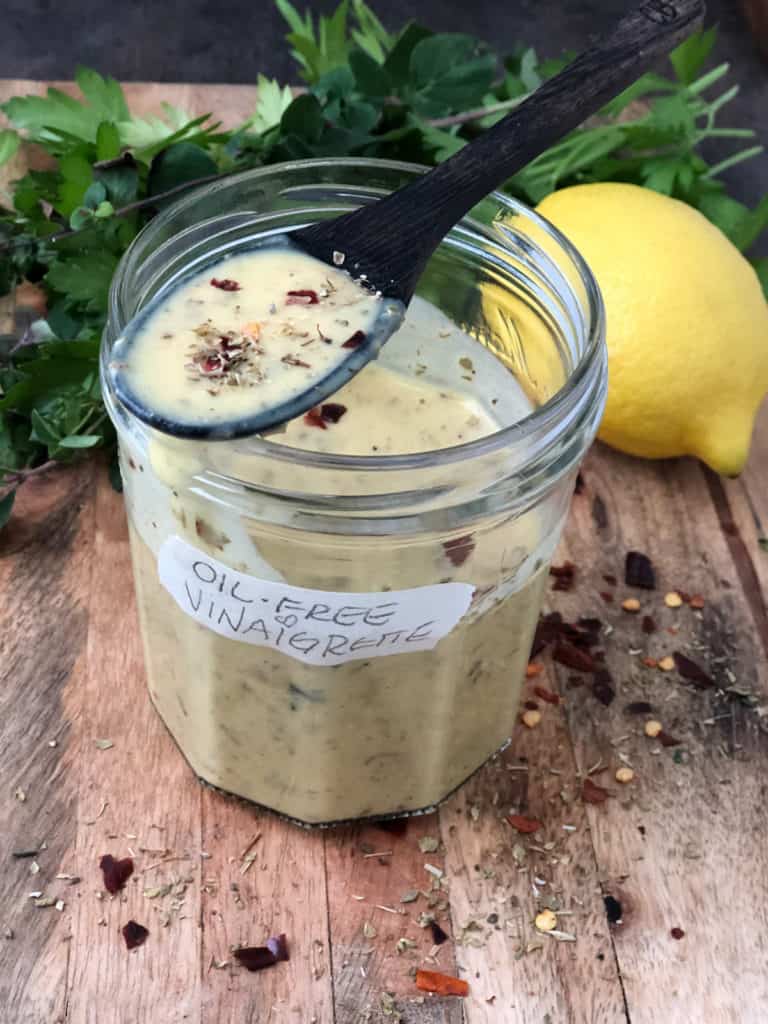 Jar of lemon vinaigrette with spoonful on top.