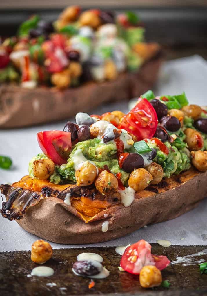 Stuffed sweet potatoes with avocado and black beans on baking sheet.
