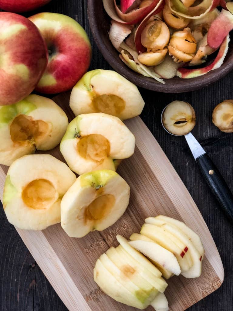 Peeled, cored and sliced apples on a cutting board.