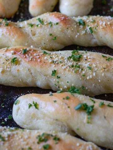 Twisted garlic butter breadsticks with fresh Italian herbs.