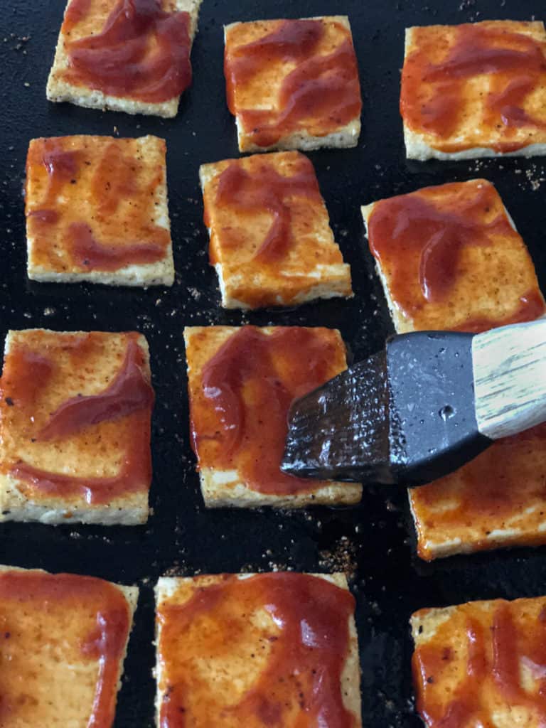 BBQ sauce being brushed on tofu slabs.