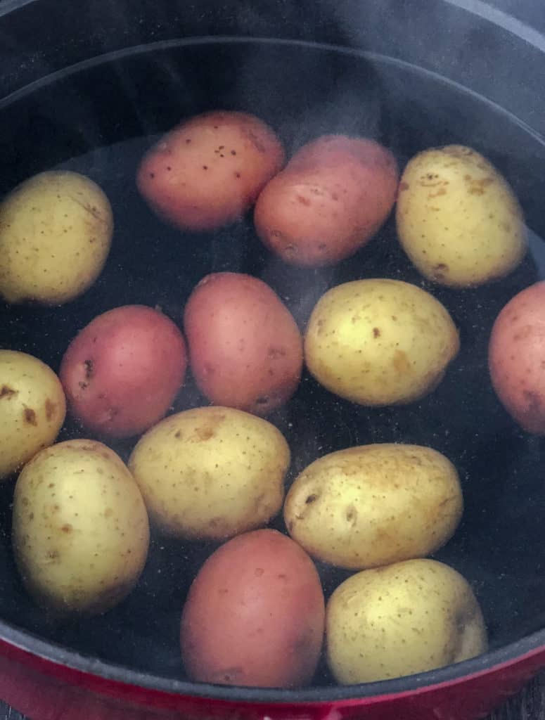 Red and golden potatoes boiling in pot.