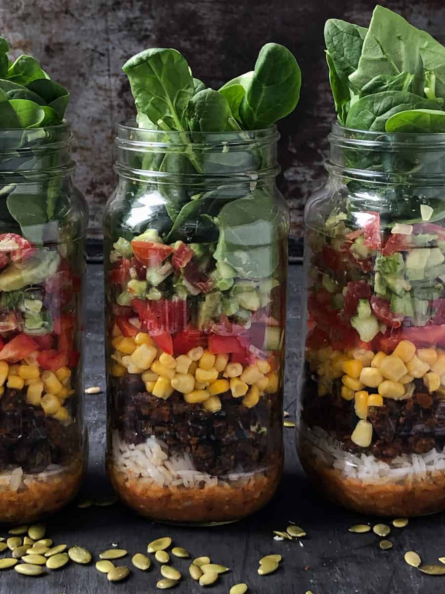 Jars of salad with beans corn and greens.