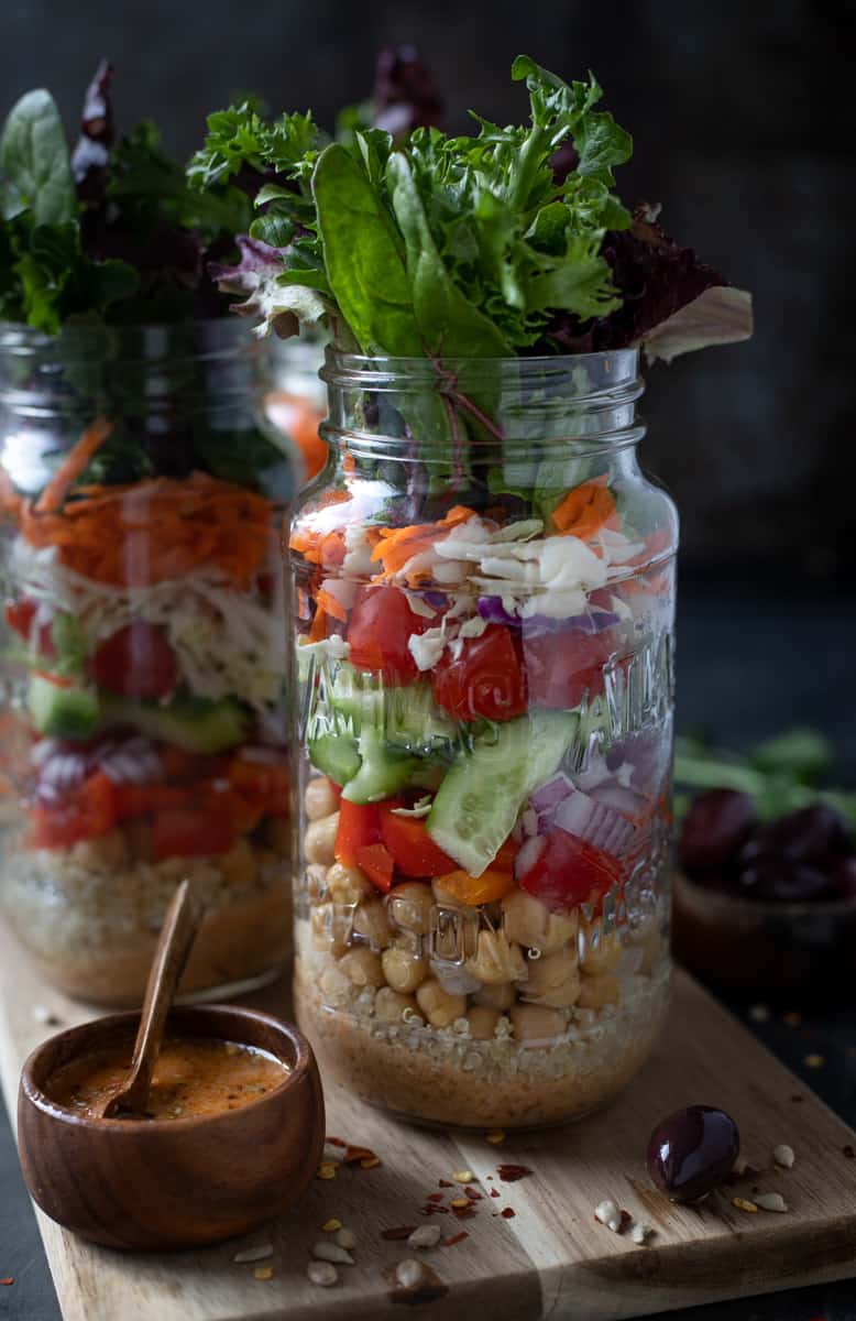 Jars of salad ingredients, rice, and beans.