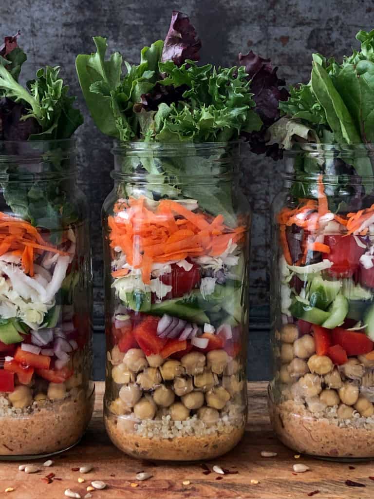 Three jars of salad with chickpeas and vegetables.