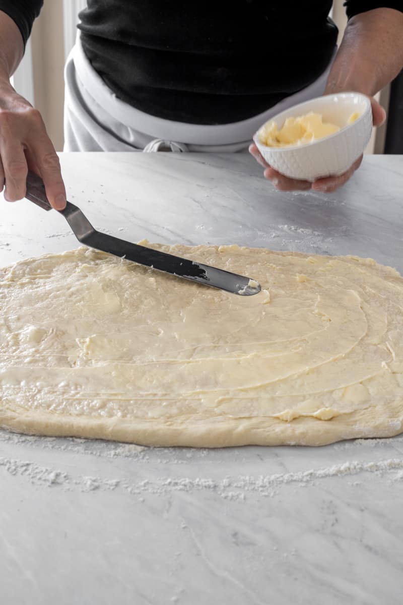 Smearing butter on cinnamon roll dough.