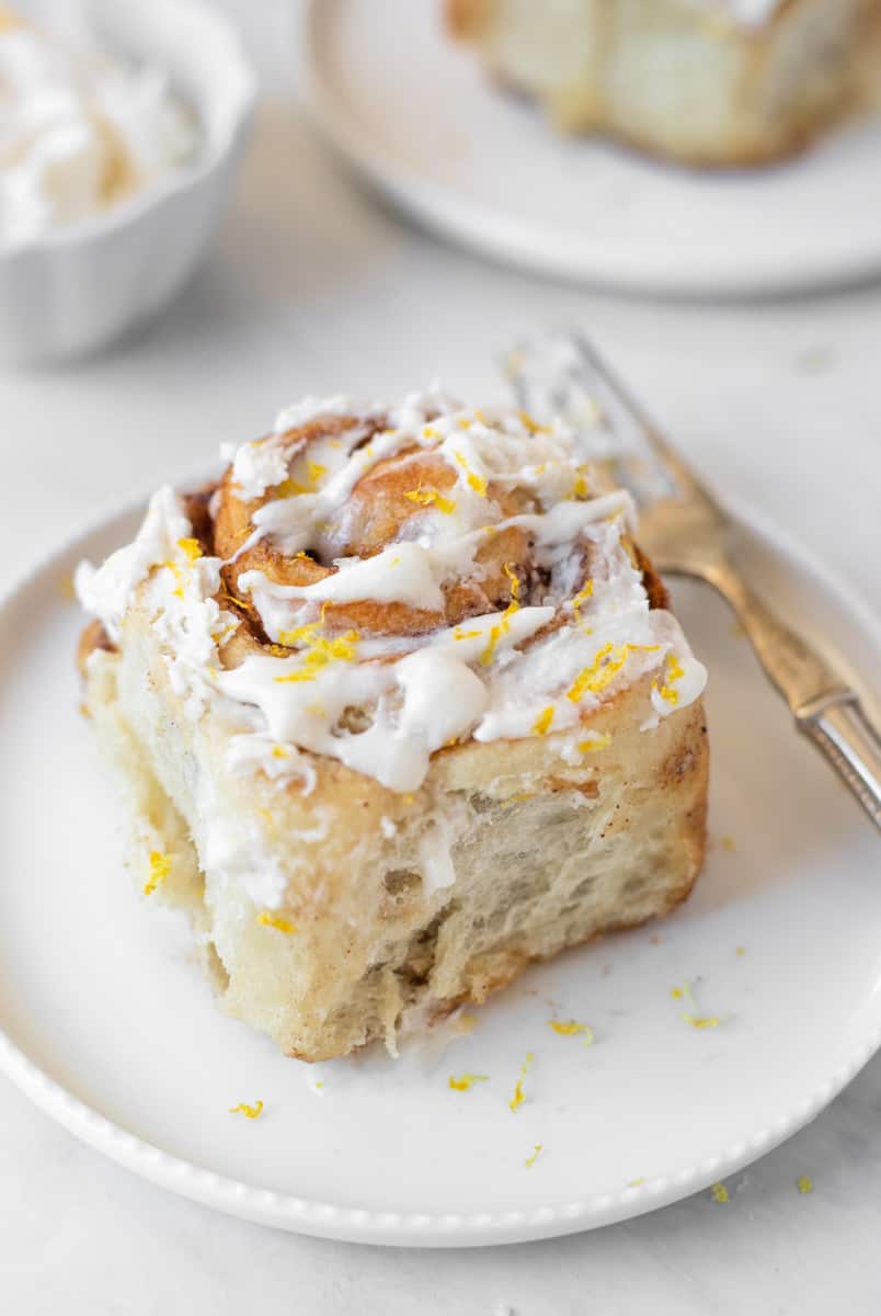 Single cinnamon roll served on a plate with a fork.