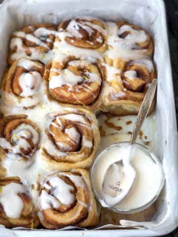 Frosting drizzled on pan of cinnamon rolls.