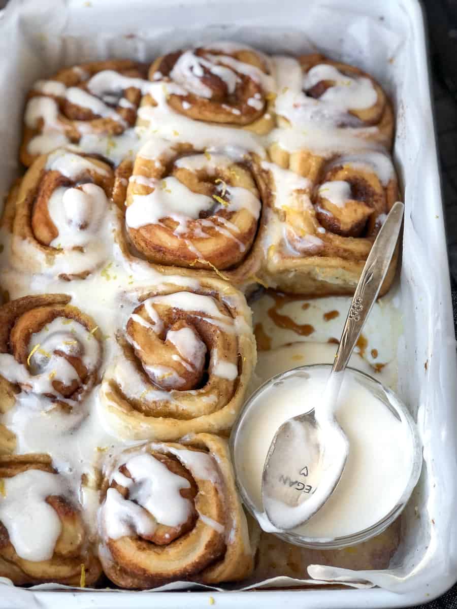 Frosting drizzled on pan of cinnamon rolls. 