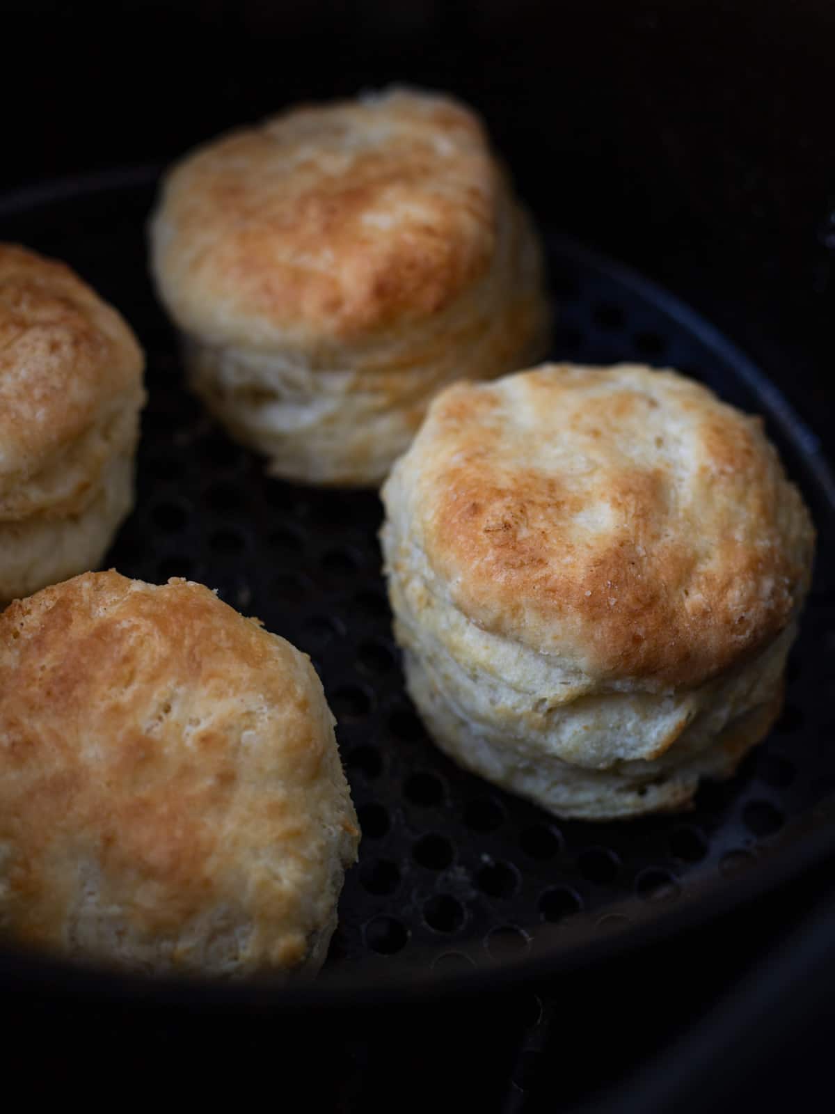 Freshly baked biscuits in basket of air fryer.