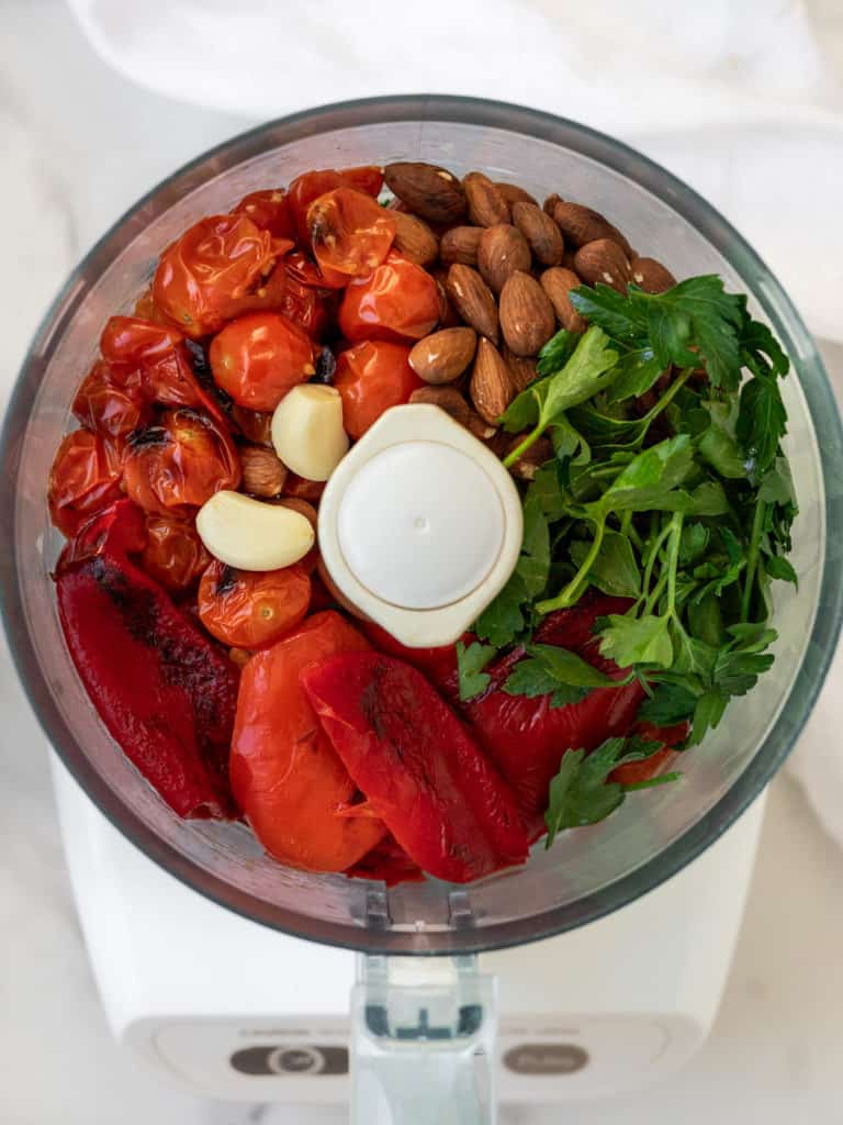 Red peppers, tomatoes and almonds in food processor bowl.